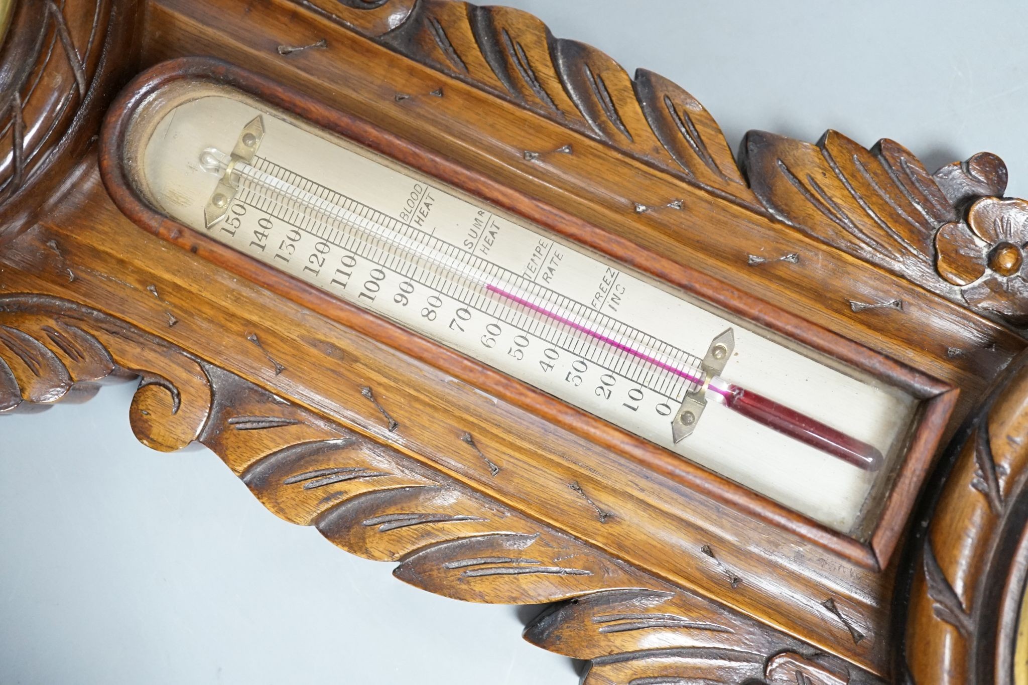 A Victorian carved walnut aneroid barometer with timepiece